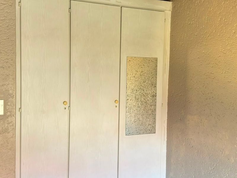 A bedroom interior featuring built-in cupboards with textured wall finishes, requiring cosmetic updates to improve the overall aesthetic and condition.