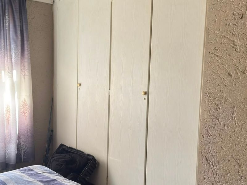 A bedroom featuring built-in cupboards with a textured wall finish and natural light from the window.