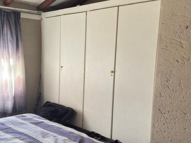 A bedroom featuring a large built-in wardrobe with white doors and textured wall finishes.