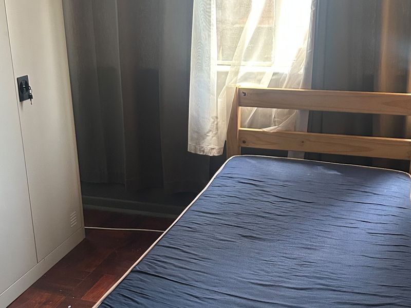A bedroom featuring parquet flooring and a window with natural light.