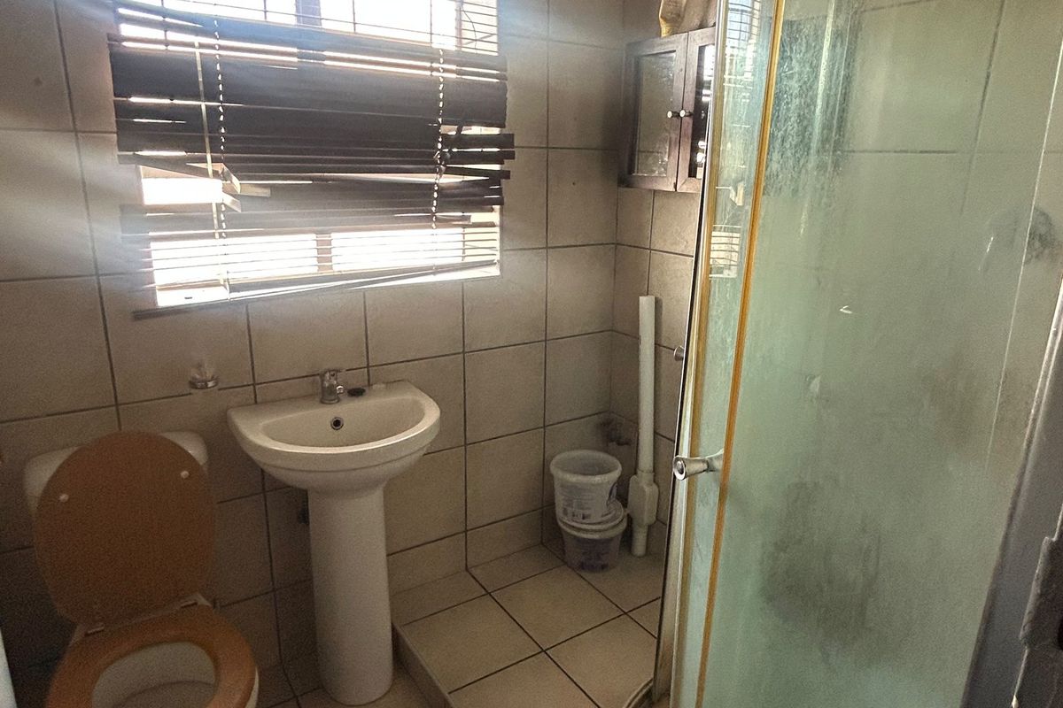 A functional bathroom featuring a pedestal basin, toilet, and shower enclosure with tiled finishes throughout.