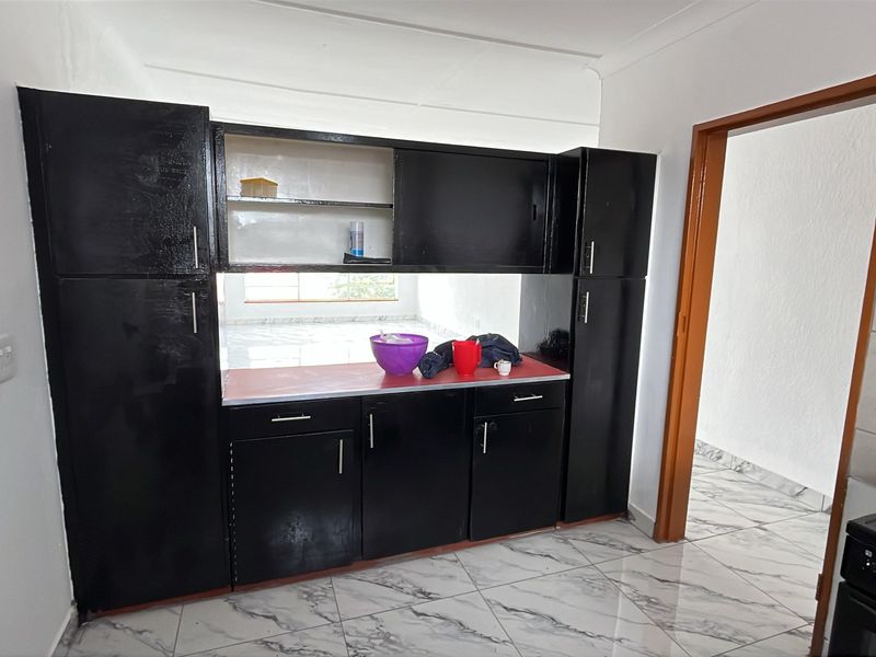 A kitchen area featuring black built-in cabinetry, tiled flooring, and a functional electric stove, offering potential for modern updates.