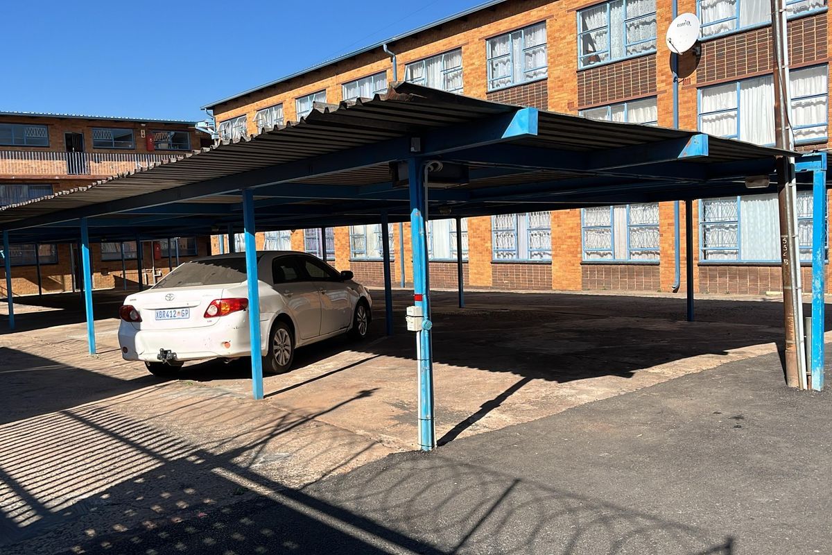 Covered parking area with a metal carport structure situated within the apartment complex grounds.