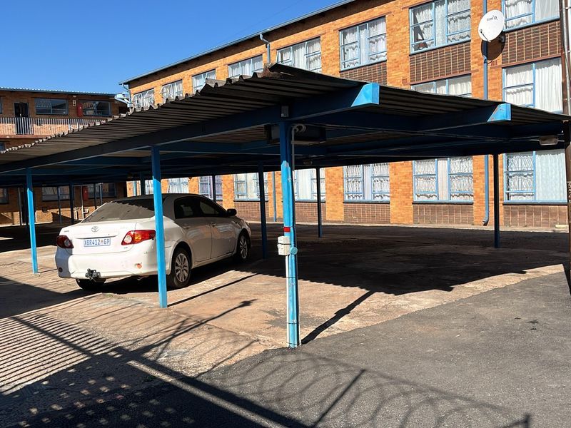 Covered parking area with a metal carport structure situated within the apartment complex grounds.