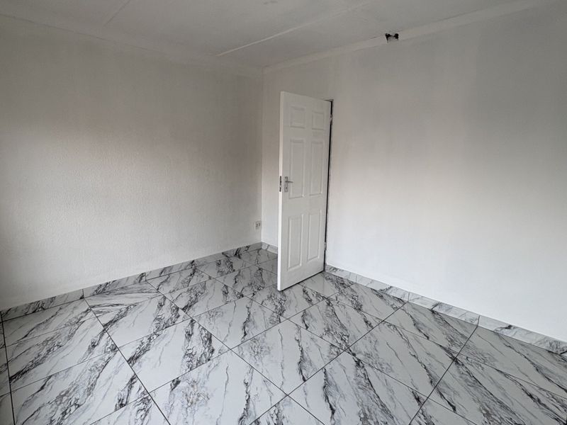 An empty bedroom featuring modern marble-effect floor tiles and a clean, neutral interior finish, ready for personalization.
