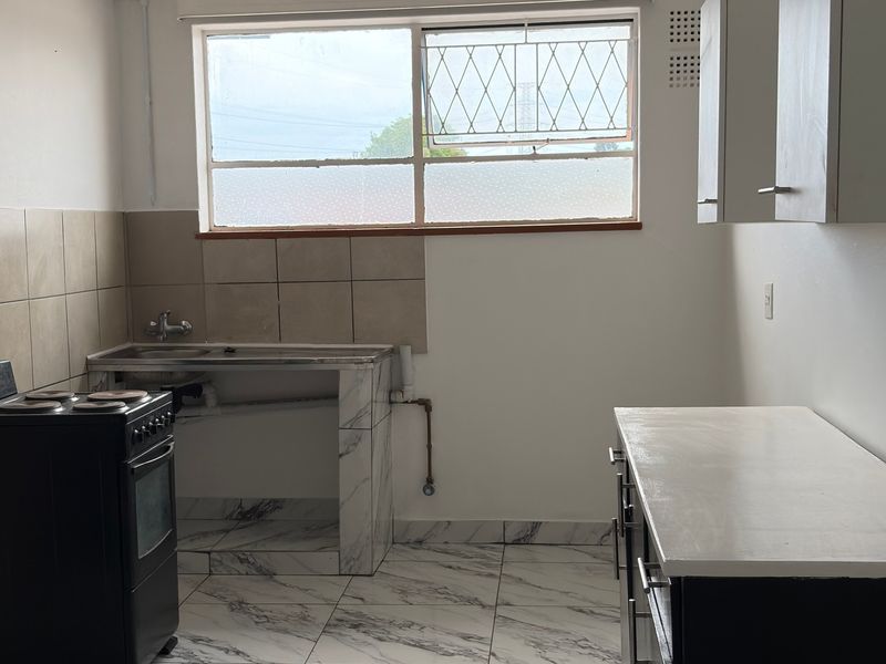 A functional kitchen space featuring marble-look floor tiles, a stainless steel sink, and built-in cabinetry, offering a blank canvas for modern updates.