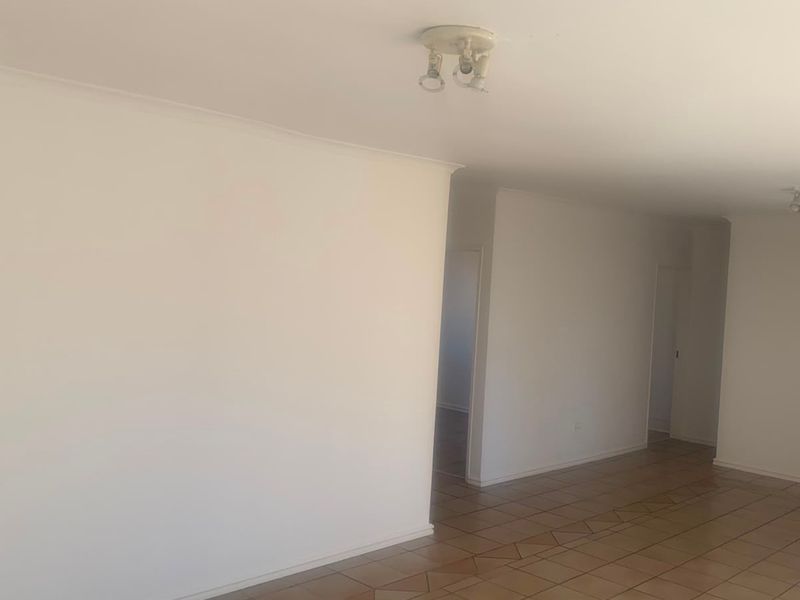 A spacious, empty living area featuring neutral walls and ceramic tile flooring, providing a blank canvas for interior design and personalization.