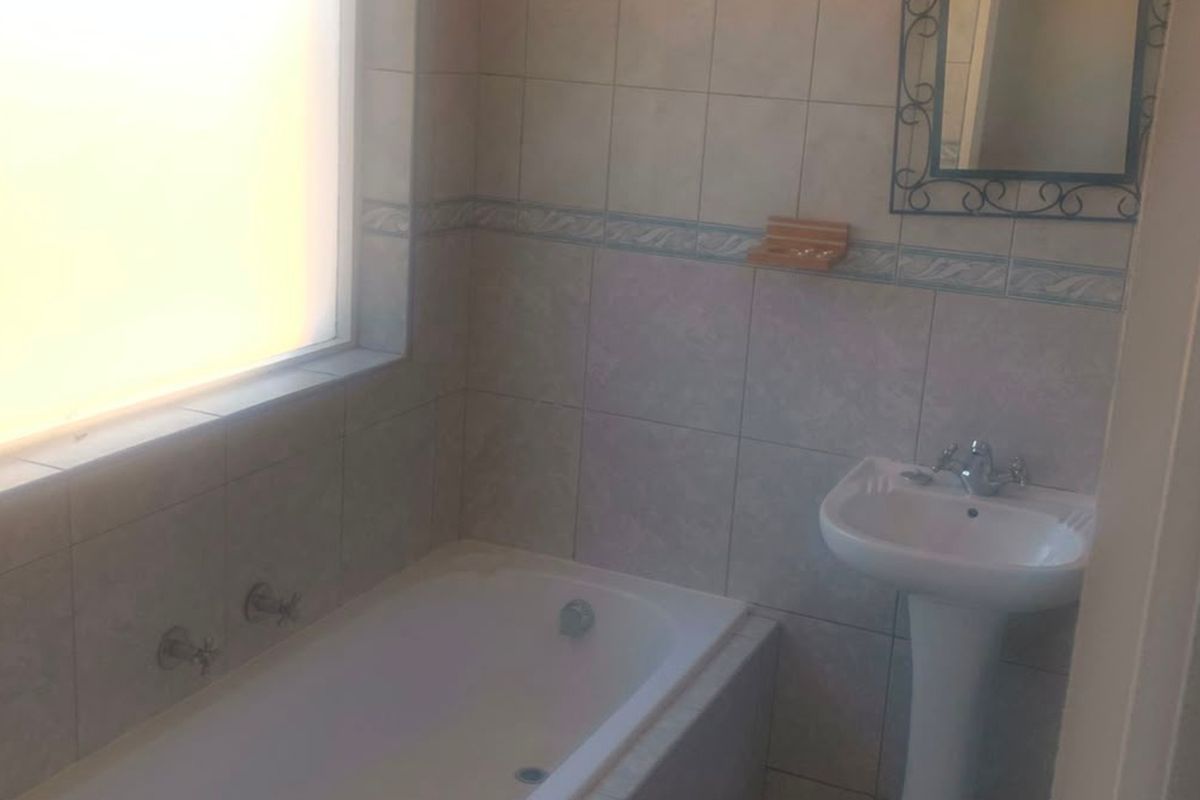 A functional bathroom featuring a built-in bathtub, pedestal basin, and tiled wall finishes.