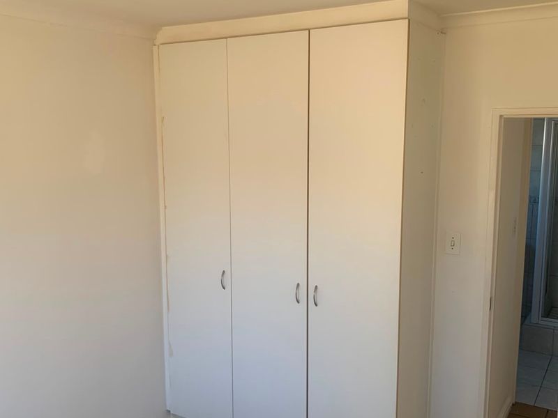 A simple bedroom featuring a white built-in wardrobe and neutral wall finishes, providing a clean canvas for interior design.