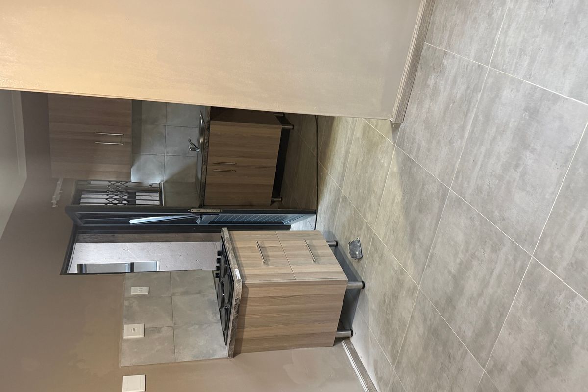 A compact kitchen area featuring built-in cabinetry, a gas hob, and tiled flooring, currently awaiting final finishing touches.