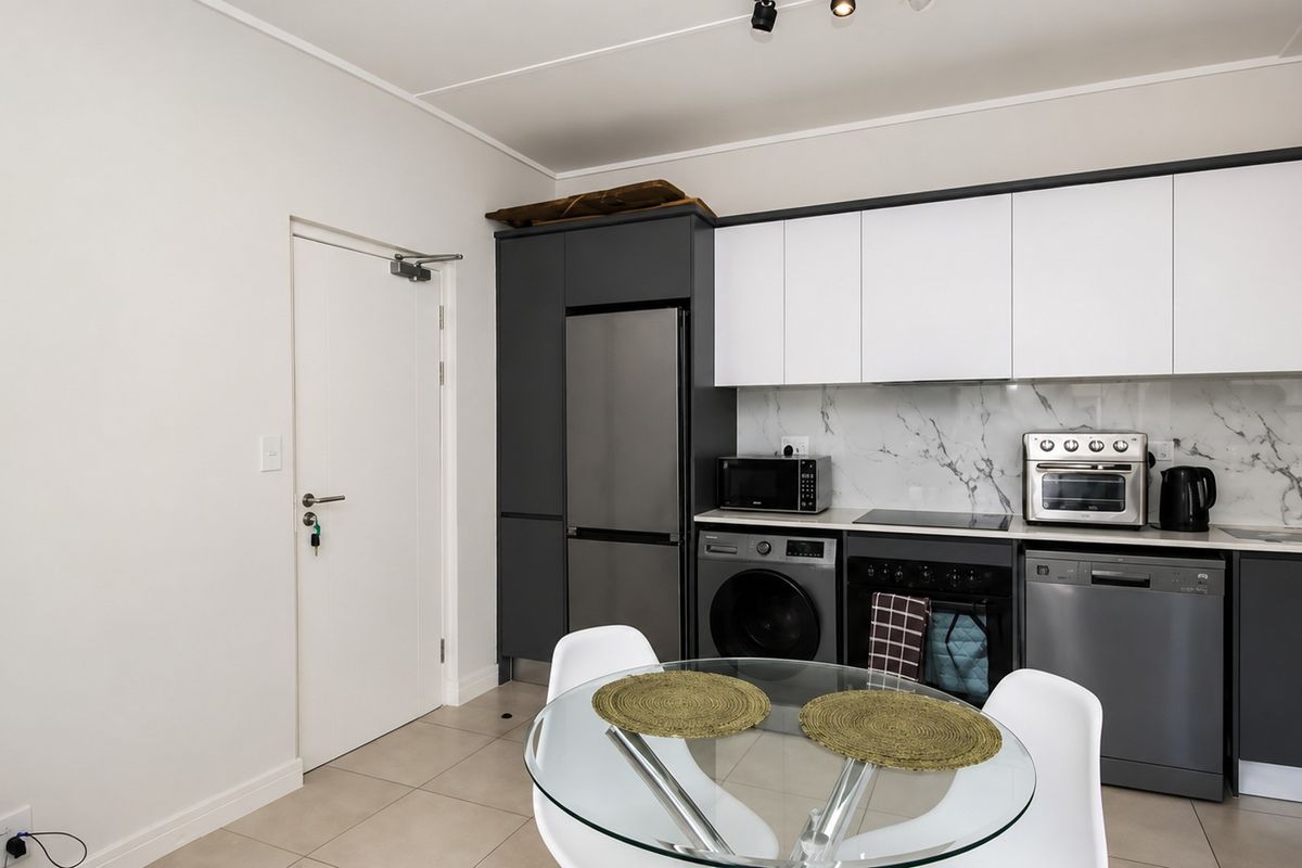 Modern kitchen featuring sleek two-tone cabinetry, marble-look backsplash, integrated appliances, and tiled flooring in a clean, contemporary layout.