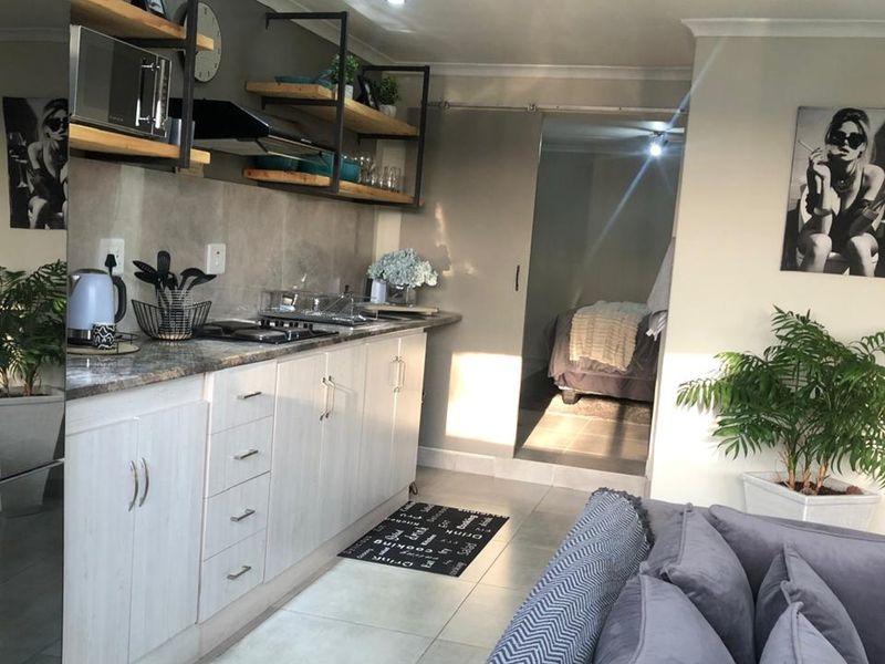 Modern open-plan kitchen featuring stone countertops, gas hob, extractor fan, and sleek cabinetry, seamlessly flowing into the adjacent living and bedroom areas.