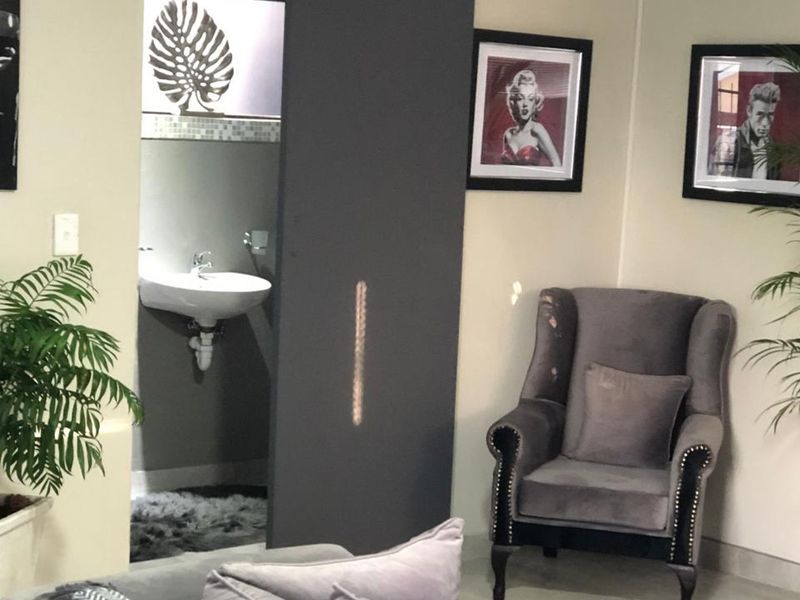 A view into a bathroom featuring a wall-mounted basin with a chrome mixer tap, accessed via a sliding door from the adjacent living area.