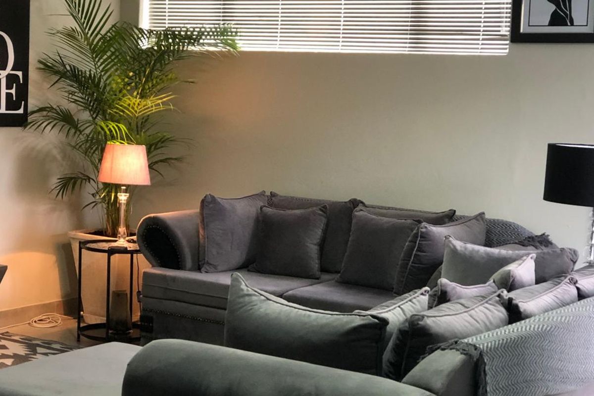 A comfortable living room area featuring neutral wall finishes and horizontal venetian blinds for adjustable natural light control.