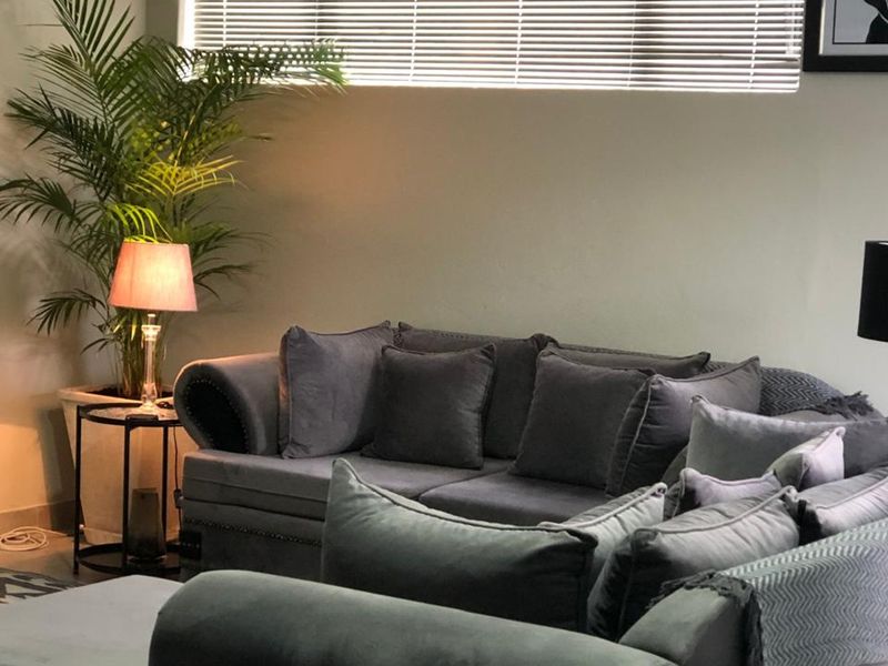 A comfortable living room area featuring neutral wall finishes and horizontal venetian blinds for adjustable natural light control.
