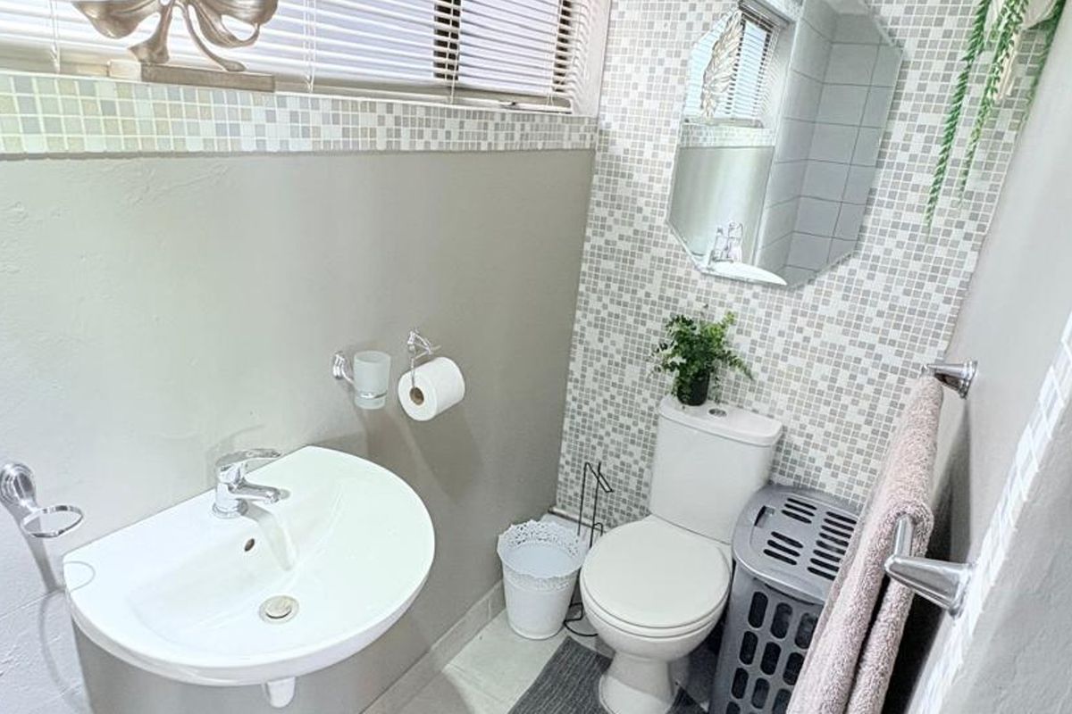 Compact bathroom featuring a pedestal washbasin, toilet, and decorative mosaic tile accents.