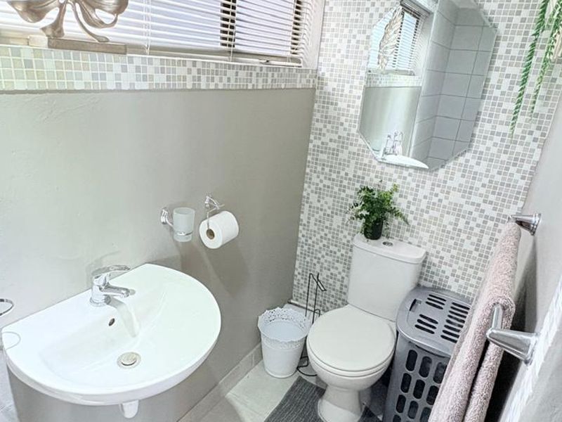 Compact bathroom featuring a pedestal washbasin, toilet, and decorative mosaic tile accents.