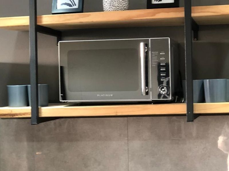 A close-up view of kitchen open shelving with a tiled splashback, providing functional storage space.