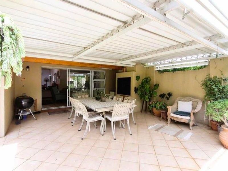 A covered outdoor patio featuring tiled flooring and a built-in braai, providing a functional space for alfresco dining and entertaining.