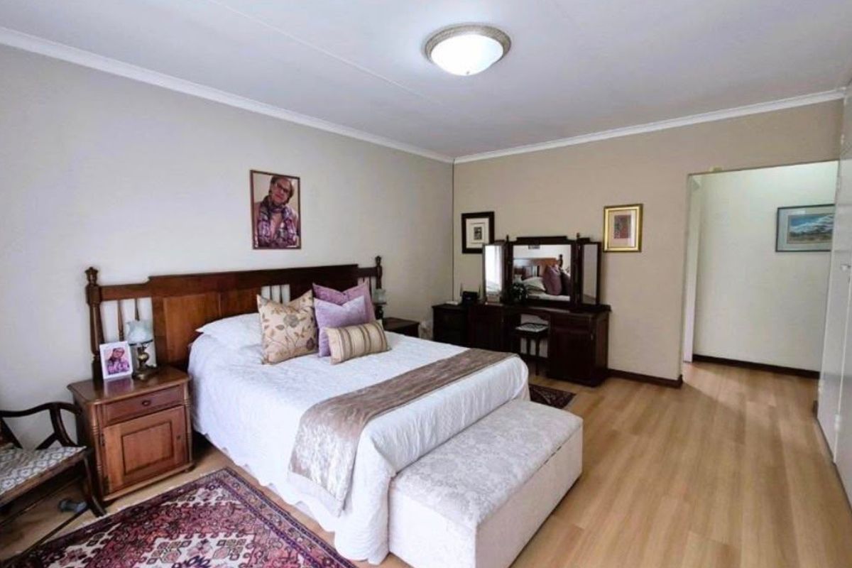 A spacious bedroom featuring light laminate flooring, neutral wall tones, and built-in storage cupboards.