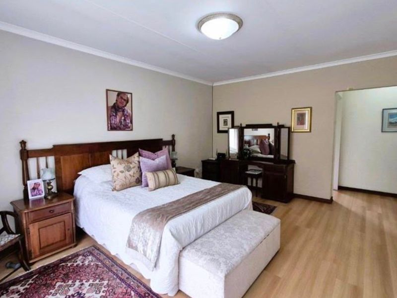 A spacious bedroom featuring light laminate flooring, neutral wall tones, and built-in storage cupboards.