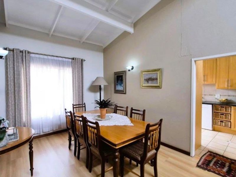 Dining room featuring vaulted ceilings and laminate flooring, with an adjacent view into the kitchen area.
