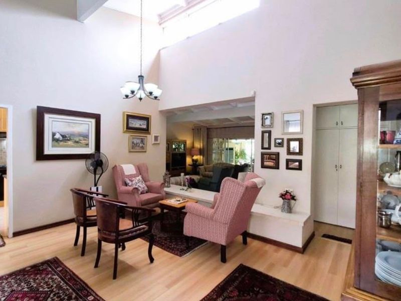 Open plan living area featuring vaulted ceilings with skylights, adjacent kitchen with built-in cabinetry, and light laminate flooring throughout.