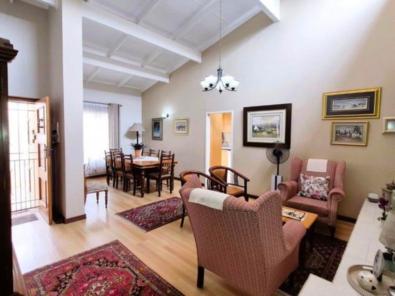Spacious open-plan living and dining area featuring high vaulted ceilings with exposed beams and light laminate flooring.