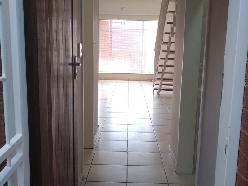 An entrance area featuring tiled flooring and an open staircase leading to the upper level, providing a bright and functional transition space.
