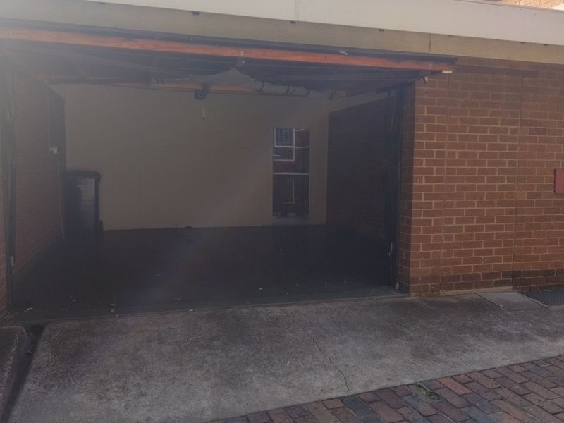 A functional single-car garage featuring exposed brick walls and a concrete driveway, providing secure off-street parking.