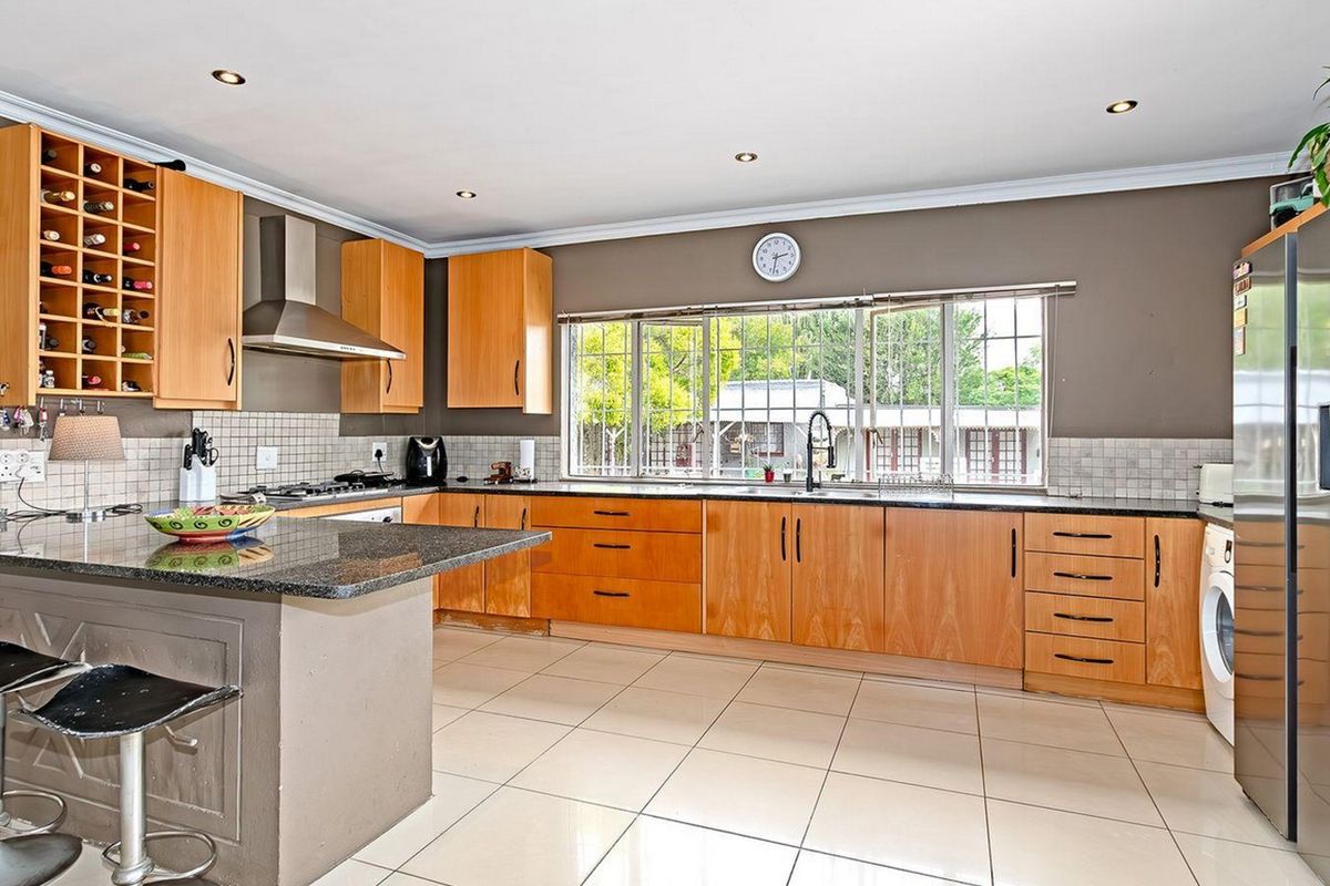 Spacious kitchen featuring wooden cabinetry, granite countertops, a gas hob, and a breakfast nook, offering a functional layout with ample storage space.