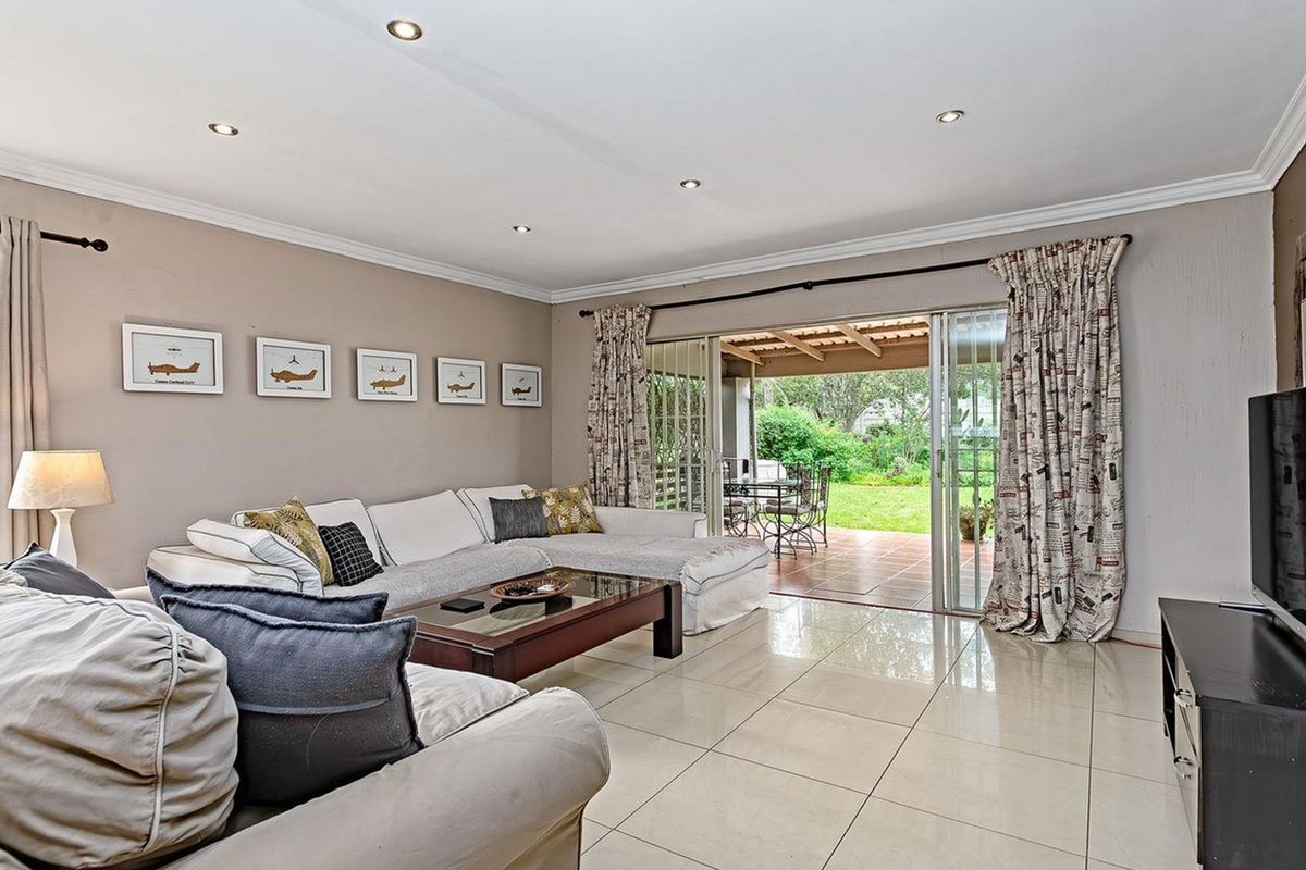 Spacious living room featuring large format floor tiles, recessed downlighting, and sliding glass doors providing direct access to the covered patio and garden.