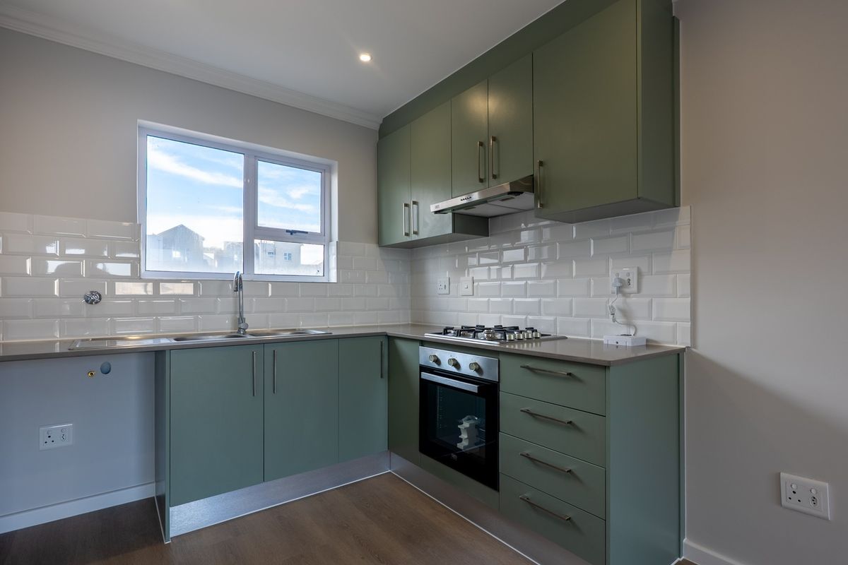Modern kitchen featuring sage green cabinetry, subway tile backsplash, gas hob, built-in oven, and stainless steel sink with ample counter space.