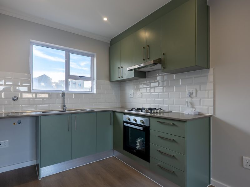 Modern kitchen featuring sage green cabinetry, subway tile backsplash, gas hob, built-in oven, and stainless steel sink with ample counter space.