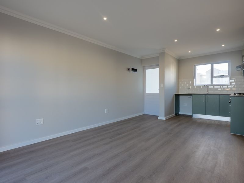 Modern open-plan living area featuring laminate flooring, recessed lighting, and a contemporary kitchen with green cabinetry and subway tile backsplash.