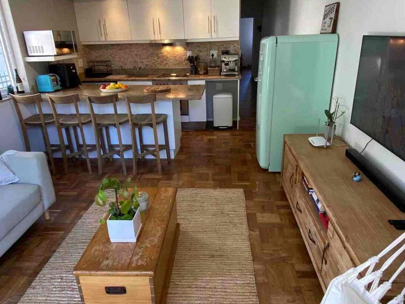 Open-plan living area featuring a modern kitchen with stone countertops, breakfast bar, and classic parquet flooring throughout the space.