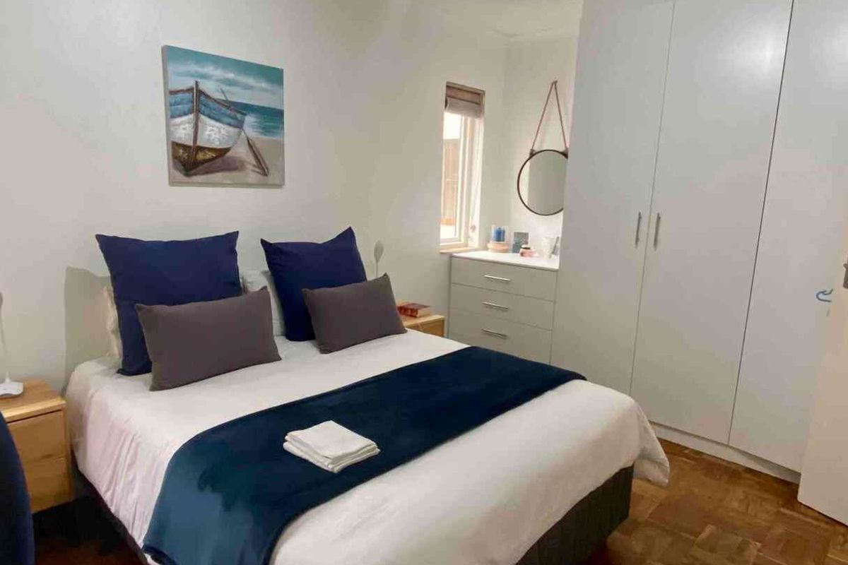A well-maintained bedroom featuring built-in cupboards and classic parquet flooring, offering a comfortable and functional living space.