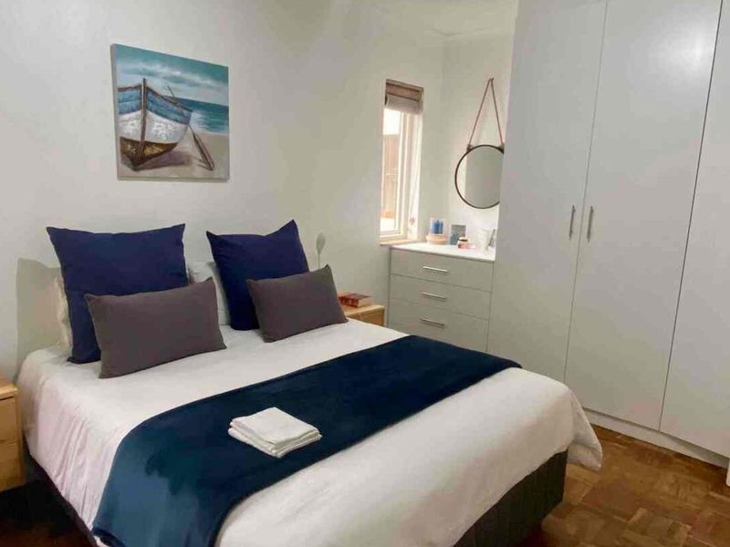 A well-maintained bedroom featuring built-in cupboards and classic parquet flooring, offering a comfortable and functional living space.