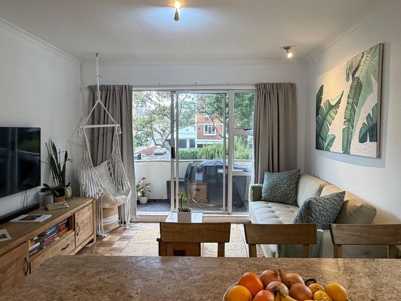 Open plan living area featuring parquet flooring, coving, and a large sliding glass door providing access to a private balcony.