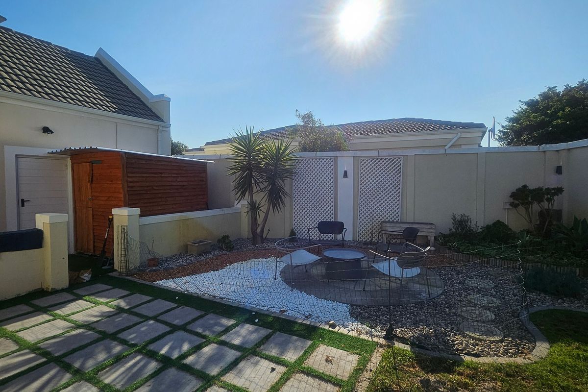 A rear garden area featuring a paved patio, boundary walls with decorative trellis panels, and a wooden storage shed.