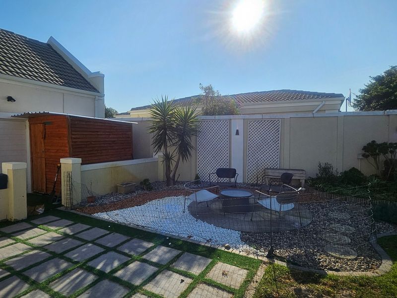 A rear garden area featuring a paved patio, boundary walls with decorative trellis panels, and a wooden storage shed.