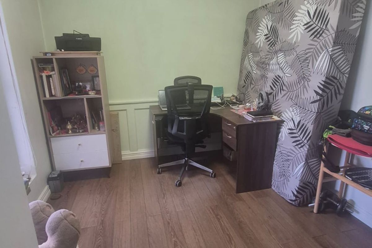 A bedroom featuring laminate flooring and wainscoting, currently utilized as a home office space.