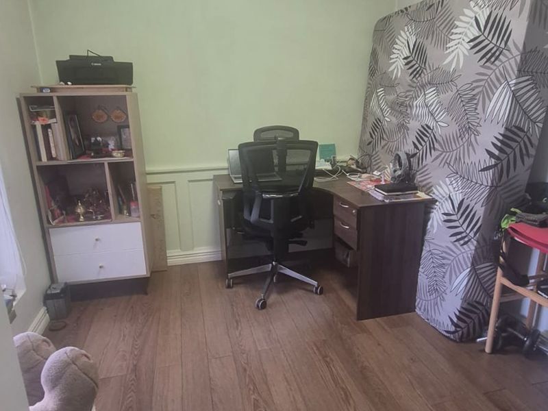 A bedroom featuring laminate flooring and wainscoting, currently utilized as a home office space.