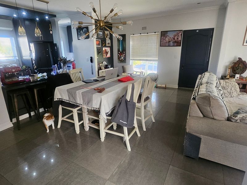 Spacious open-plan living and dining area featuring large format floor tiles, modern pendant lighting, and a functional kitchen with a central island.