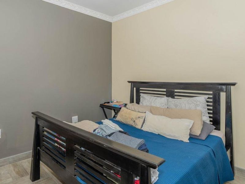 A bedroom featuring tiled flooring and decorative ceiling cornicing, providing a neutral foundation for personal styling.