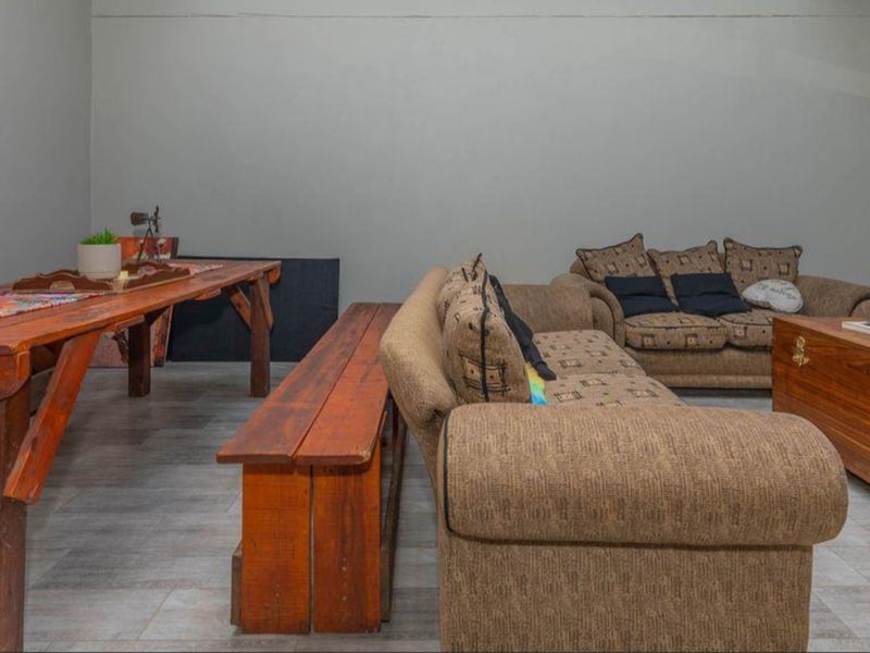 A spacious living area featuring neutral wall finishes and tiled flooring, offering a versatile layout for comfortable seating and dining arrangements.