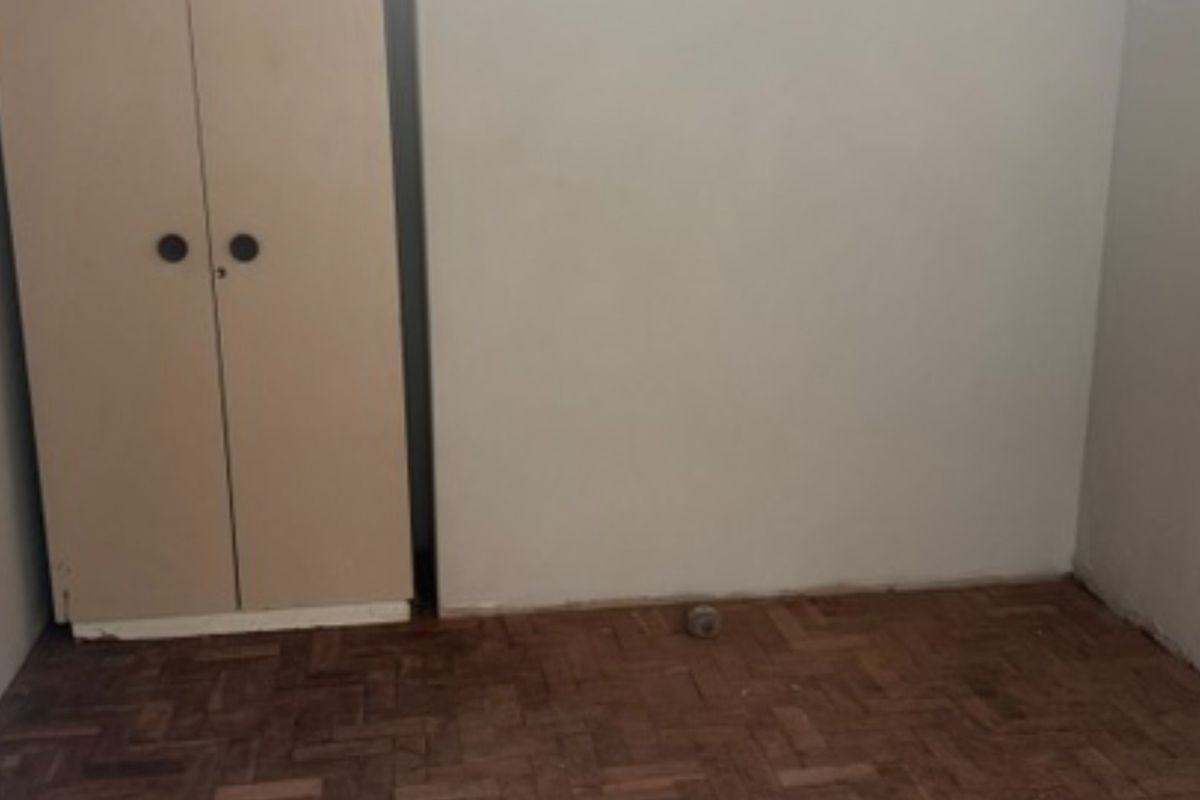 A vacant bedroom featuring original parquet flooring and a built-in cupboard, offering a blank canvas for renovation and interior design updates.
