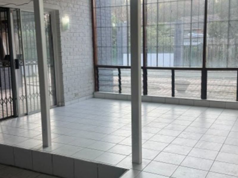 An enclosed patio area featuring tiled flooring, brick walls, and large windows, providing a versatile space for outdoor living.
