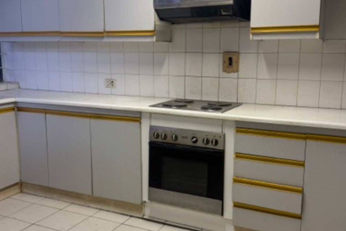 A dated kitchen featuring built-in cabinetry, an electric hob, an oven, and a tiled backsplash, offering a functional layout ready for modernization.