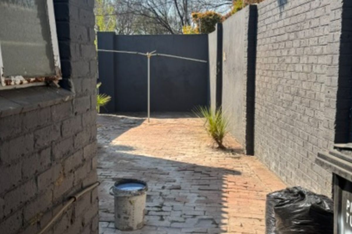 A private rear courtyard featuring painted brick boundary walls, brick paving, and a rotary clothesline, offering a blank canvas for outdoor landscaping.